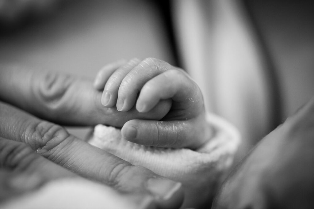A baby sleeping and holding hands